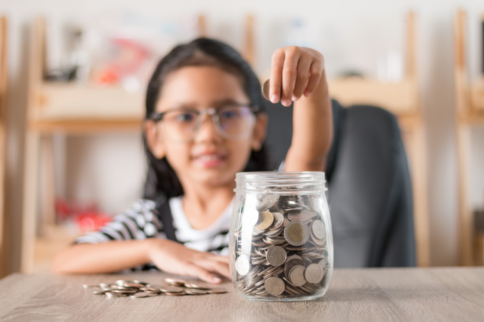 A child adding a coin to a savings jar